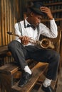 Black jazz musician sitting with saxophone