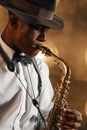 Black jazzman in hat plays the saxophone on stage Royalty Free Stock Photo