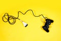 Black joystick, game controller with broken cable isolated on yellow background Royalty Free Stock Photo