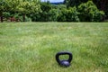 Black kettle bell on a green lawn, ready for an outdoor workout Royalty Free Stock Photo