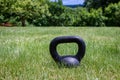 Black kettle bell on a green lawn, ready for an outdoor workout Royalty Free Stock Photo