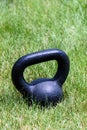 Black kettle bell on a green lawn, ready for an outdoor workout Royalty Free Stock Photo