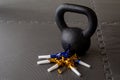 Black kettlebell on a black gym floor with blue and gold noisemakers