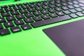 black keyboard on a green laptop. keys with letters and numbers. Detail of a laptop computer. Image detail to describe IT tools,