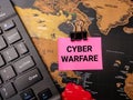 Black keyboard and sticky note with the word CYBER WARFARE on a world map background Royalty Free Stock Photo
