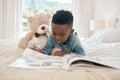 Black kid, learning and reading book in home bedroom, storytelling and knowledge. African child, boy and read books for