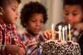 Black kid touching cake's candle.