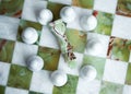 Black king fallen down, surrounded by white pawns on marble chess board from white and green marble. Business strategy with team Royalty Free Stock Photo