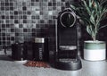 Black kitchen with home coffee machine and beans with cup and olive tree plant Royalty Free Stock Photo