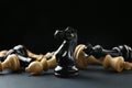 Black knight among fallen chess pieces on dark background