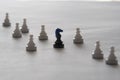 Black knight and white pawns on white background. Plastic chess items from travel set. Selective focus Royalty Free Stock Photo