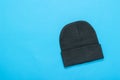 Black knitted women`s hat on a blue background. Royalty Free Stock Photo