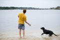 Black Labrador Dog sitting on the shore of a pond