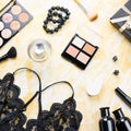 Black lace lingerie with beauty care products, make up cosmetics, jewelry in black and gold. Fashion flat lay, top view Royalty Free Stock Photo