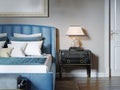 Black lacquered bedside table with table lamp and silver curly stand. The lampshade is square in shape