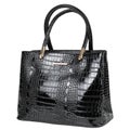 Black lacquered women`s bag made of reptile skin, with two handles, on a white background Royalty Free Stock Photo