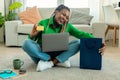 Black lady feeling happy over big sale in online shop, using laptop, showing credit card and embracing shopping bag Royalty Free Stock Photo
