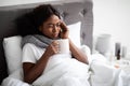 Black lady laying in bed with cup of hot drink Royalty Free Stock Photo