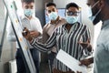 Black lady in medical mask presenting business strategy on whiteboard Royalty Free Stock Photo