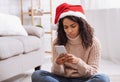 Black lady in santa hat using cellphone, looking sad Royalty Free Stock Photo