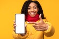 Black Lady Showing Cellphone Screen Posing On Yellow Background