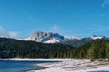 Black lake at the edge of a coniferous forest at the foot of the snowy mountains. National Park Durmitor, Montenegro Royalty Free Stock Photo
