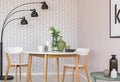 Black lamp above chairs and wooden table in simple dining room interior with flowers. Real photo