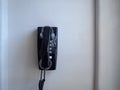 Black landline phone and receiver hanging on white wall Royalty Free Stock Photo