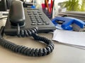 Black landline telephone with a tube, buttons and a wire on the work table at the office desk with office supplies. Business work Royalty Free Stock Photo