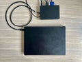 A black laptop connected to a black docking station with a USB cable. Clean office desk. Efficient workstation layout Royalty Free Stock Photo