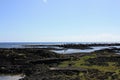 Black lava rock shoreline at low tide at Richardson`s Beach Park in Hawaii Royalty Free Stock Photo