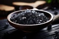 Black lava salt is a salt with a distinctive glossy black color, coarse grain in a wooden bowl