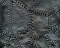 Black leather background sewn from small leather pieces with leather thread