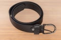 Black leather belt with semicircular frame buckle on light surface