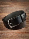 Black leather belt on a wooden brown background Royalty Free Stock Photo