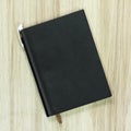 Black leather book with white pen on wood background. Blank template of hardcover book Royalty Free Stock Photo