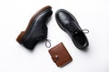 Black leather derby shoes with polyurethane soles and a brown purse with a button on a white background