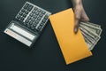 On the black leather desk a calculator, the girl holds in her hand a yellow envelope with money, salary for work