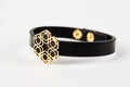 Black leather and gold cuff bracelet on white background with copy space