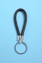 Black leather keychain on light blue background, top view