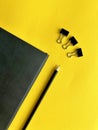 black leather notepad, pencil, paper clips, paper clips on yellow background, business Royalty Free Stock Photo