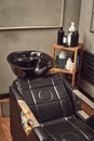 Black leather seat with wash basin in a barbershop interior with towels and shampoo on the side. Royalty Free Stock Photo