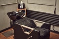 Black leather seat with wash basin in a barbershop interior with towels and shampoo on the side. Royalty Free Stock Photo