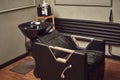 Black leather seat with wash basin in a barbershop interior with towels and shampoo on the side. Royalty Free Stock Photo