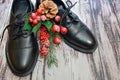 Black leather shoes and Christmas decor on wooden background. Pair of stylish women`s boots and spruce twig with Christmas toys Royalty Free Stock Photo