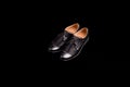 Black leather shoes isolated on black background. Men elegant pair of shoes.