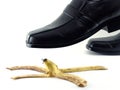 close-up businessman leather shoes about to step on banana peel isolated on white background