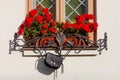 Black leather small trendy bag handing outdoor on balcone with red flowers in a cafe.  Fashion detail Royalty Free Stock Photo