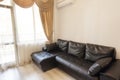 Black leather sofa near a large window with sheers, curtains and draperies. Classic living room furniture