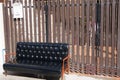 Black leather sofa and wooden armrest chair with white mailbox on brown background.